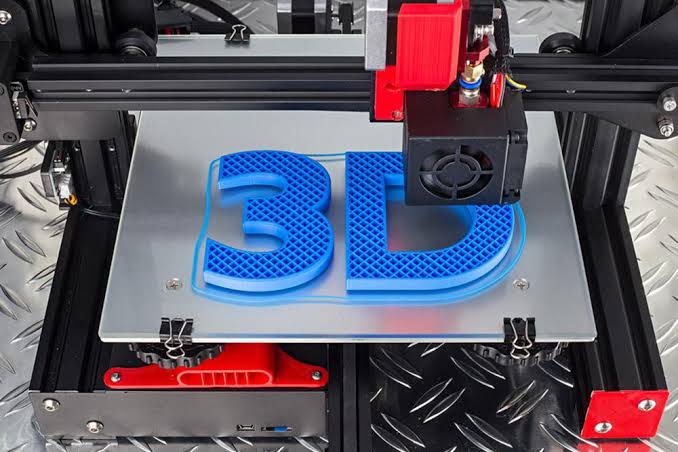 A 3D printer mid-print, extruding a blue 3D-lettered logo