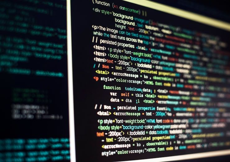 A close-up, angled view of a monitor showing colorful HTML and JavaScript code