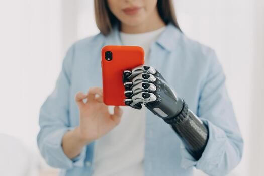 A woman using a bionic prosthetic hand to hold a phone