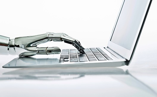 A robotic hand typing on a laptop keyboard