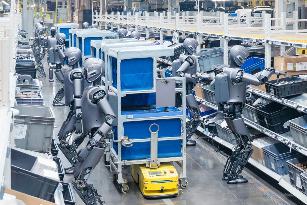 A row of humanoid robots handling bins and totes alongside carts in a warehouse